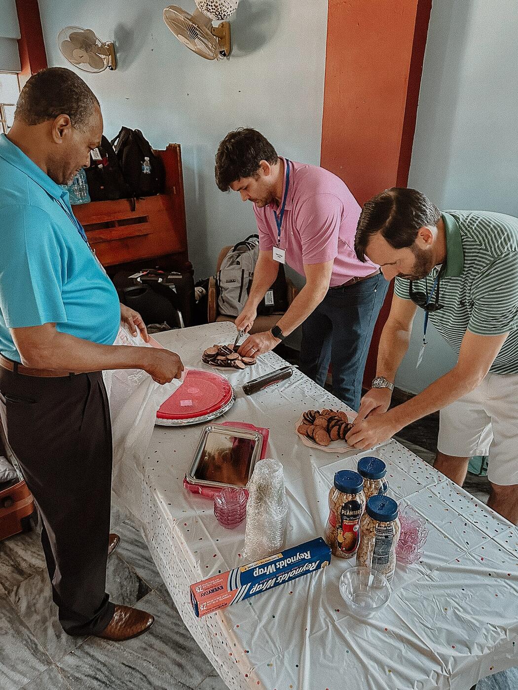 Three men preparing food to serve.